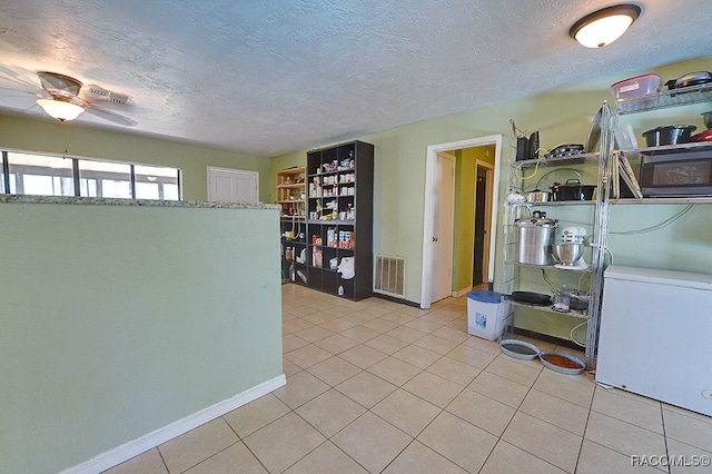 kitchen with ceiling fan, light tile patterned flooring, and a textured ceiling