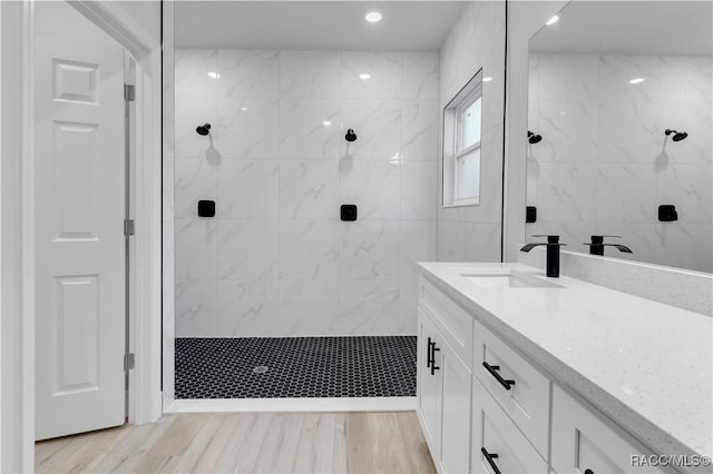 bathroom with a tile shower and vanity