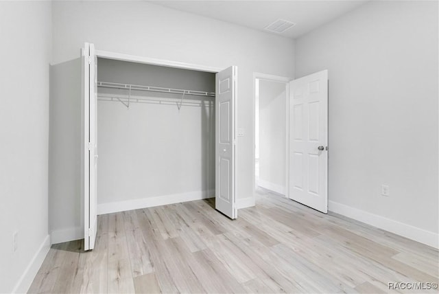 unfurnished bedroom with light wood-type flooring and a closet