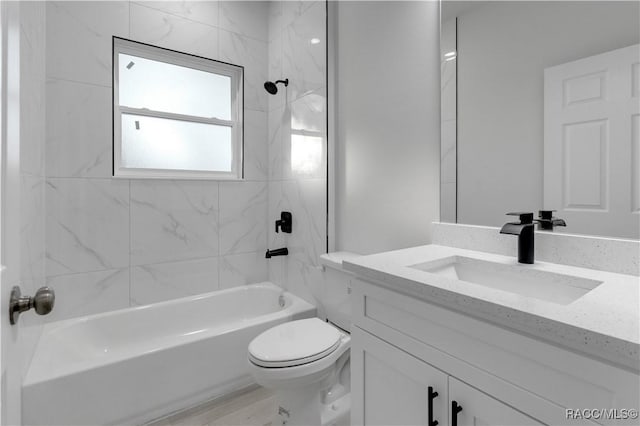 full bathroom featuring vanity, tiled shower / bath combo, and toilet