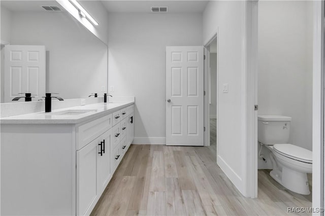 bathroom with toilet, vanity, and hardwood / wood-style floors