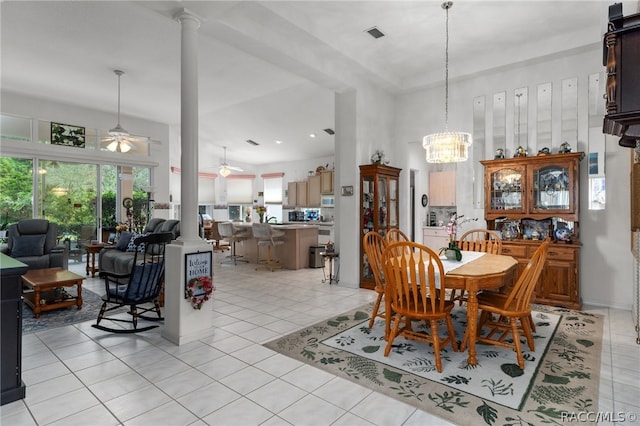 tiled dining space with ceiling fan with notable chandelier and ornate columns