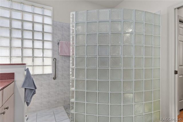 bathroom with tile patterned floors, a shower, vanity, and tile walls