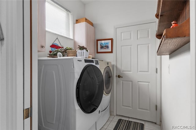 washroom featuring washer and clothes dryer, light tile patterned flooring, and cabinets