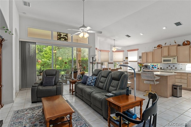 tiled living room featuring ceiling fan and a towering ceiling