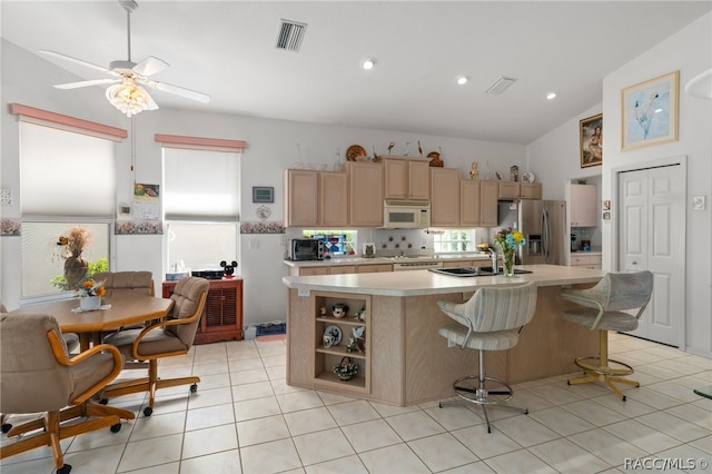 kitchen with white appliances, a healthy amount of sunlight, sink, a center island with sink, and lofted ceiling