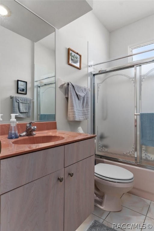 full bathroom featuring toilet, tile patterned flooring, vanity, and combined bath / shower with glass door