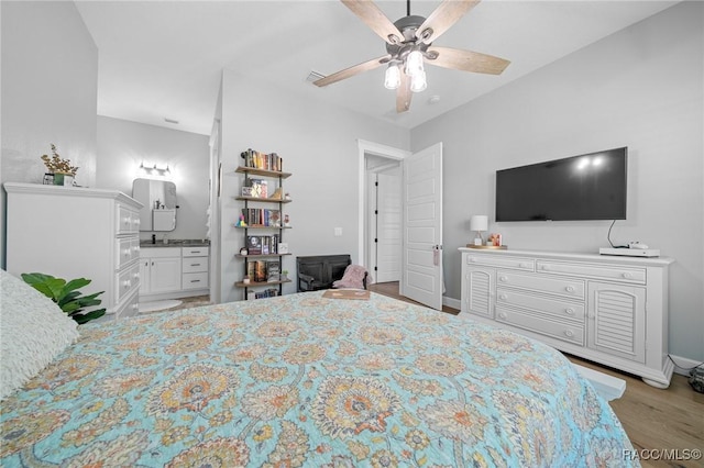 bedroom with ceiling fan, connected bathroom, light wood-style flooring, and baseboards