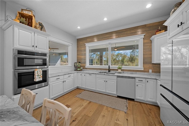 kitchen featuring double oven, light wood-style floors, a sink, and dishwashing machine