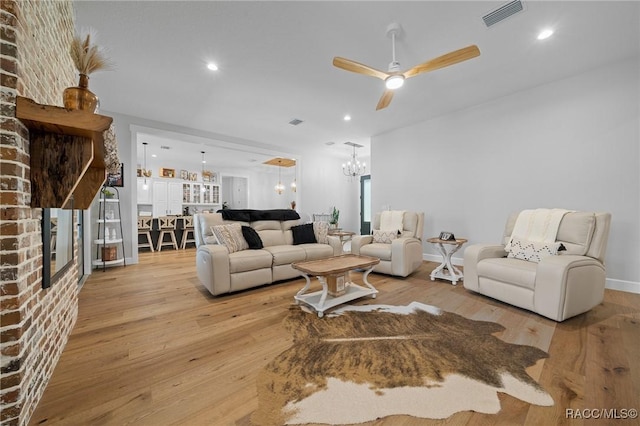 living room with baseboards, visible vents, hardwood / wood-style floors, ceiling fan with notable chandelier, and recessed lighting