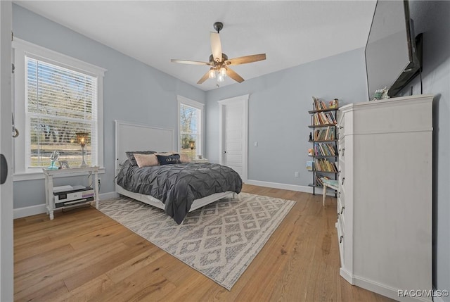 bedroom featuring light wood-style flooring, multiple windows, and baseboards