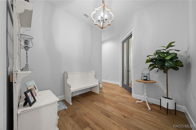 corridor with a chandelier, light wood-style flooring, visible vents, and baseboards