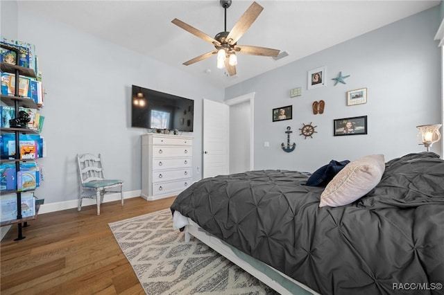 bedroom featuring visible vents, ceiling fan, baseboards, and wood finished floors