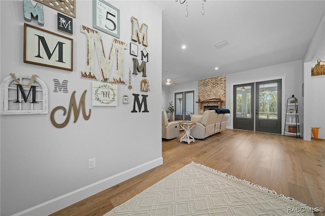 interior space featuring recessed lighting, wood finished floors, baseboards, french doors, and a brick fireplace