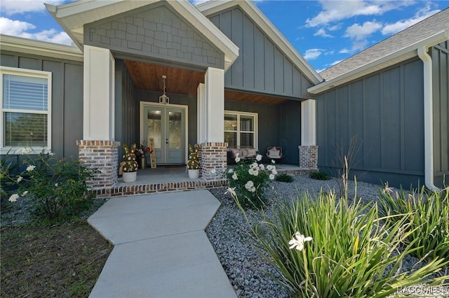 property entrance with board and batten siding, french doors, covered porch, and brick siding