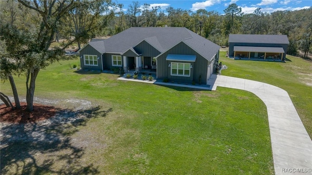 craftsman house with board and batten siding, a front yard, and concrete driveway