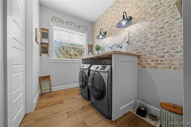 clothes washing area featuring light wood-type flooring, laundry area, baseboards, and separate washer and dryer