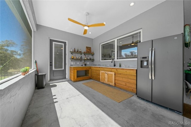 kitchen with concrete floors, a sink, light countertops, stainless steel refrigerator with ice dispenser, and open shelves