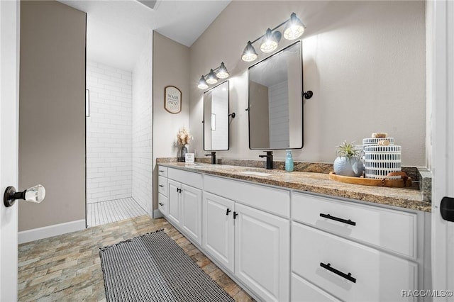 full bath with double vanity, a sink, and walk in shower