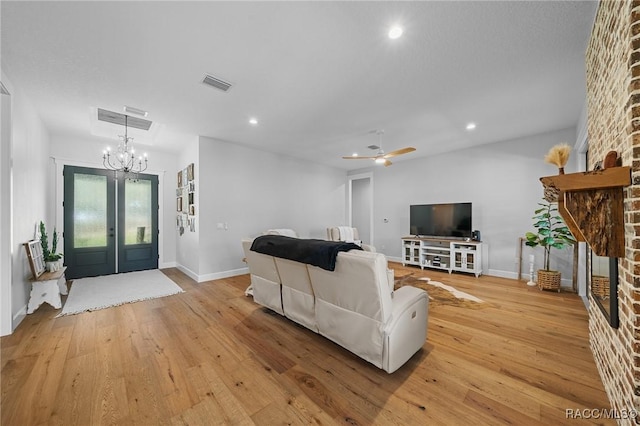 living area with light wood-type flooring, a brick fireplace, visible vents, and recessed lighting