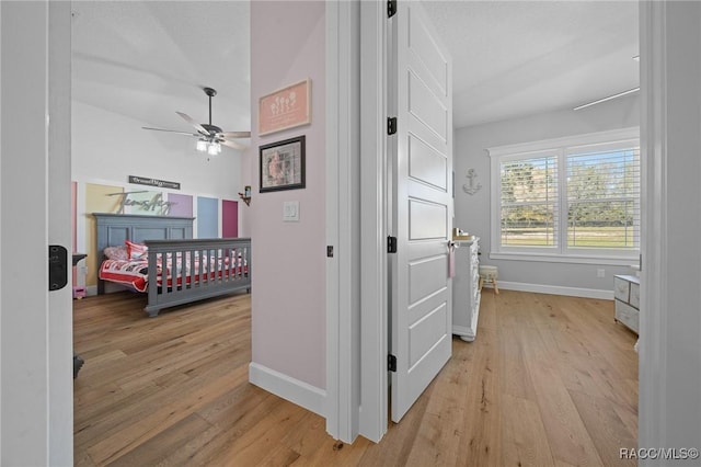 bedroom featuring a ceiling fan, light wood-style flooring, and baseboards