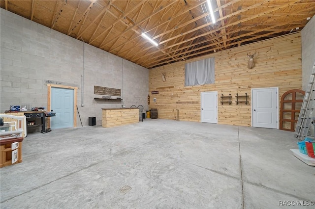 interior space featuring a garage, unfinished concrete floors, and a towering ceiling