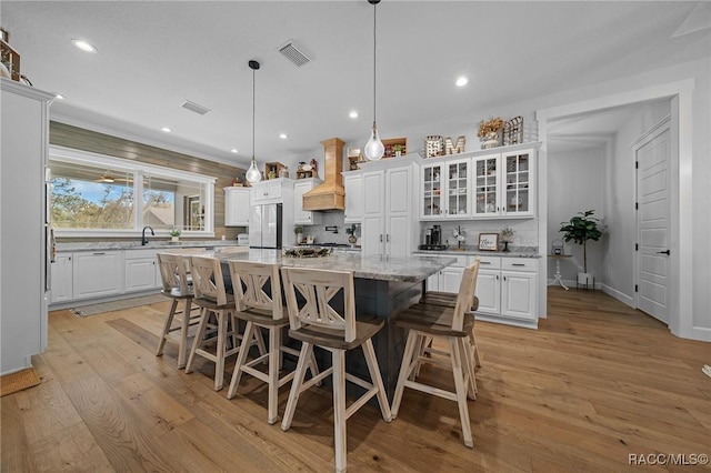 kitchen with freestanding refrigerator, visible vents, light wood finished floors, and white cabinetry