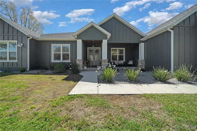 doorway to property featuring a yard, a porch, board and batten siding, and brick siding