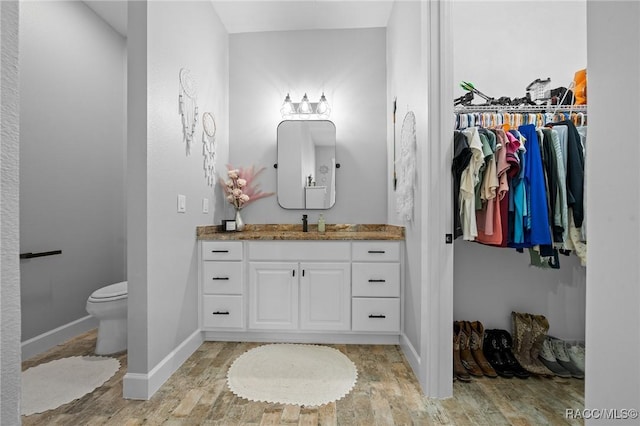 bathroom featuring baseboards, vanity, toilet, and wood finished floors