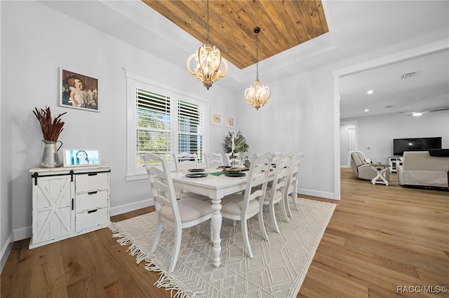 dining space featuring light wood finished floors, visible vents, baseboards, an inviting chandelier, and a tray ceiling