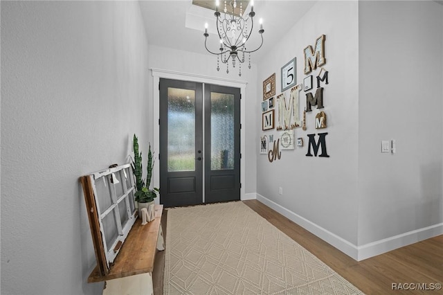 foyer entrance with an inviting chandelier, french doors, baseboards, and wood finished floors