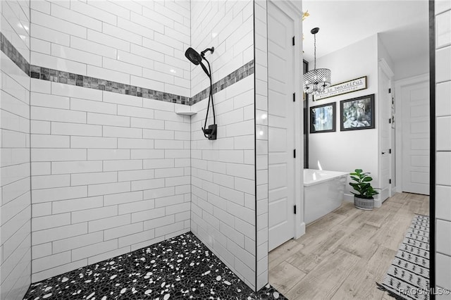 full bathroom with tiled shower, a freestanding bath, and wood finished floors