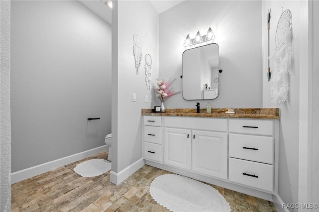 bathroom featuring toilet, wood finished floors, vanity, and baseboards