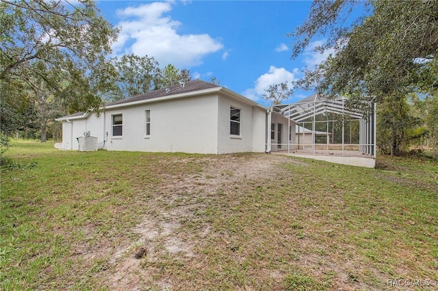 back of property featuring a lanai and a lawn