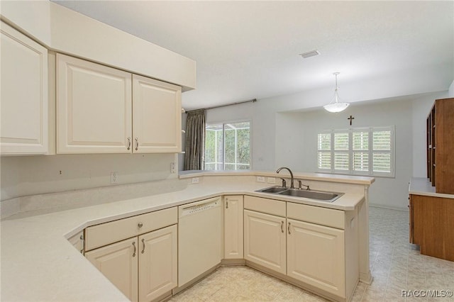 kitchen with a wealth of natural light, sink, kitchen peninsula, white dishwasher, and decorative light fixtures