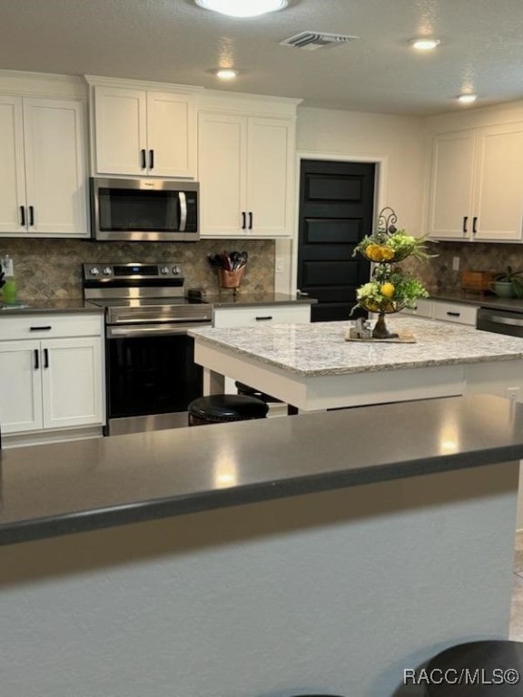 kitchen with tasteful backsplash, white cabinetry, a center island, and stainless steel appliances