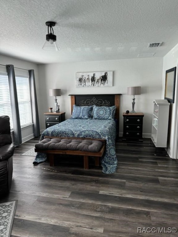 bedroom with a textured ceiling and dark hardwood / wood-style flooring