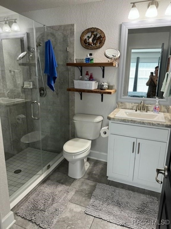 bathroom with tile patterned floors, vanity, an enclosed shower, and toilet