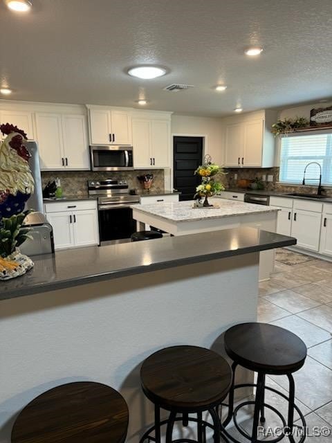 kitchen with backsplash, white cabinetry, sink, and stainless steel appliances