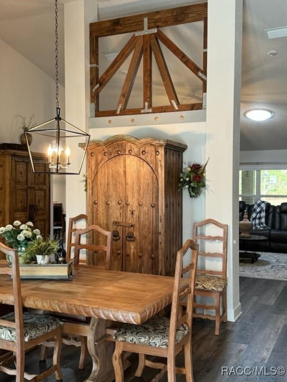 dining area with lofted ceiling, a chandelier, and dark hardwood / wood-style floors