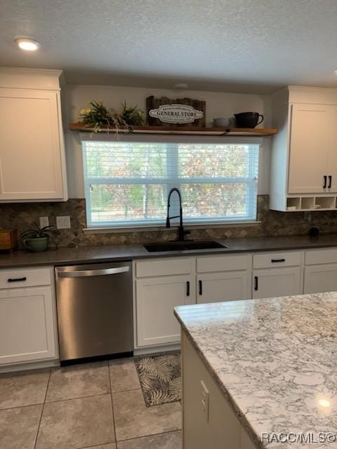 kitchen with dishwasher, light tile patterned flooring, white cabinetry, and sink