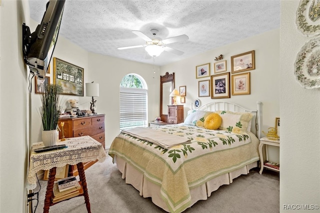 bedroom featuring light carpet, a textured ceiling, and ceiling fan