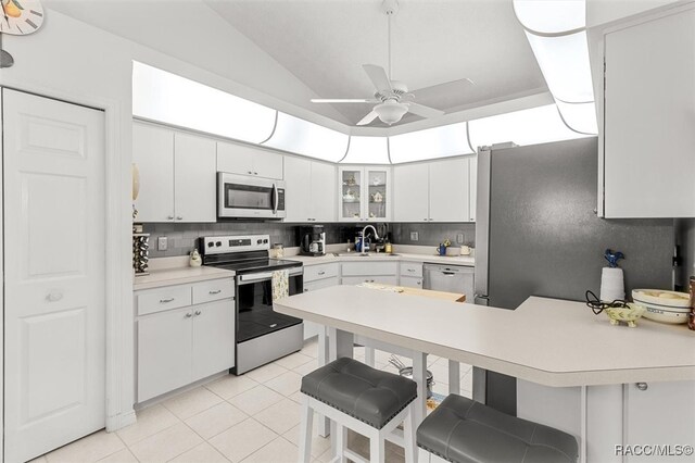 kitchen with a kitchen breakfast bar, white cabinetry, and appliances with stainless steel finishes