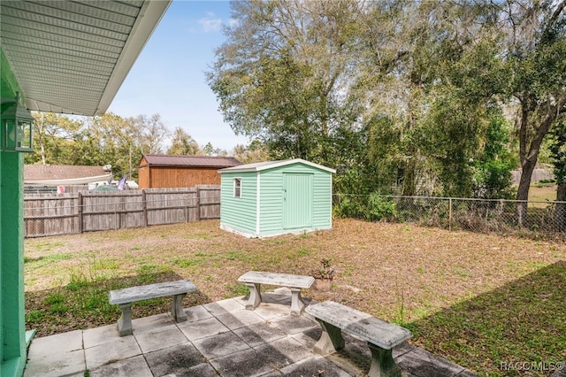 view of yard with a patio, an outbuilding, a fenced backyard, and a storage shed