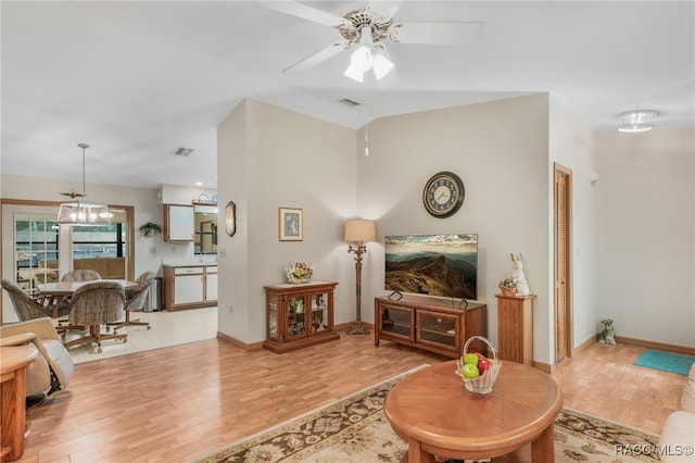 living room with wood finished floors, visible vents, baseboards, lofted ceiling, and ceiling fan with notable chandelier