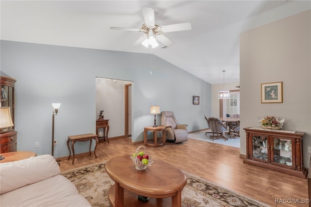 living area with a ceiling fan, lofted ceiling, wood finished floors, and baseboards