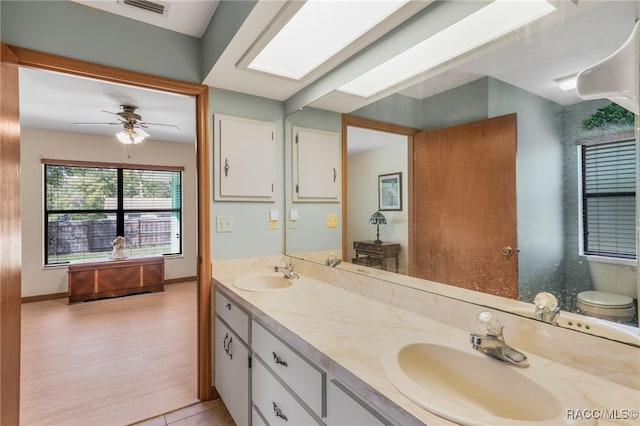 bathroom featuring a sink, visible vents, a skylight, and double vanity