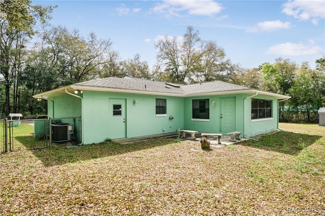 back of property with fence, stucco siding, cooling unit, a yard, and a gate