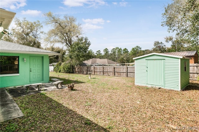 view of yard featuring an outbuilding, a fenced backyard, and a storage shed