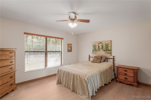 bedroom with a ceiling fan, baseboards, and light wood-type flooring